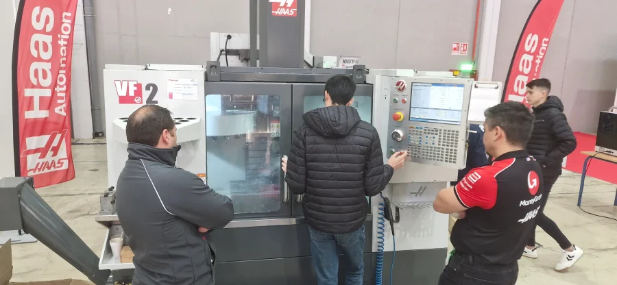 Máquina CNC Haas mecanizando pieza con 4 personas alrededor